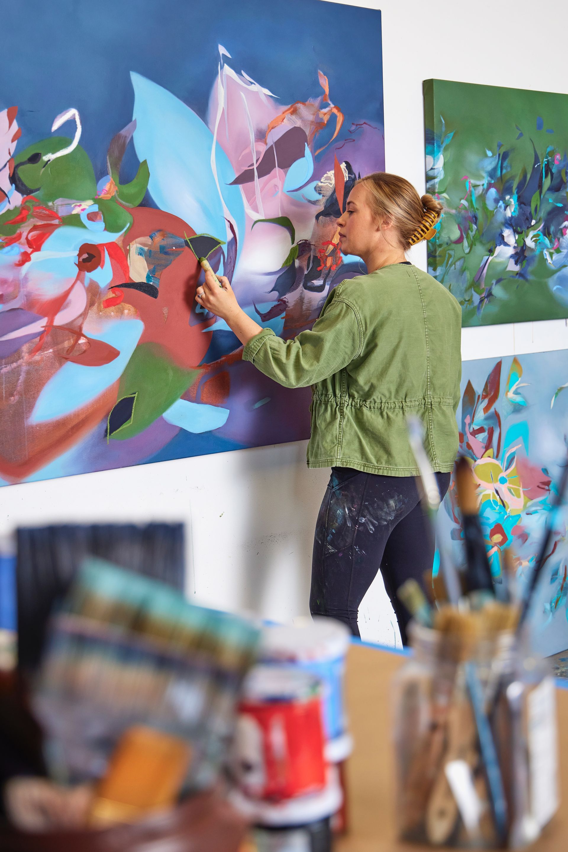 A woman is painting a picture on a wall in a studio.