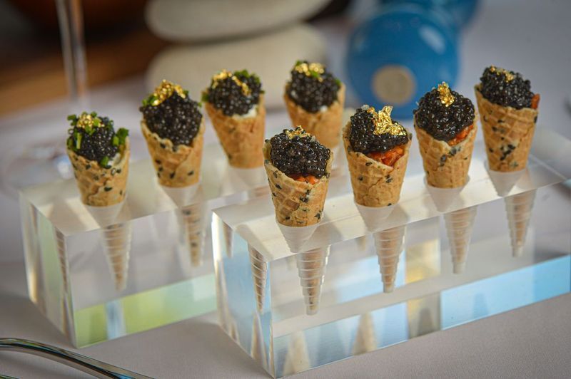 A display of ice cream cones filled with caviar on a table.