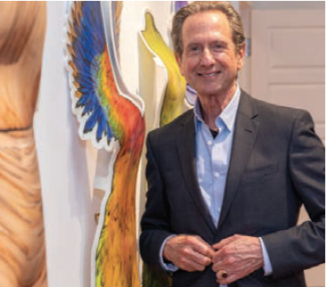 A man in a suit is standing in front of a painting of a parrot