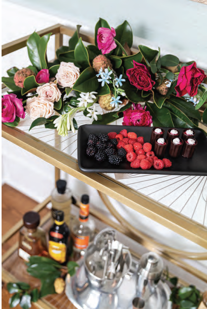 A bar cart with a tray of fruit and flowers on it.