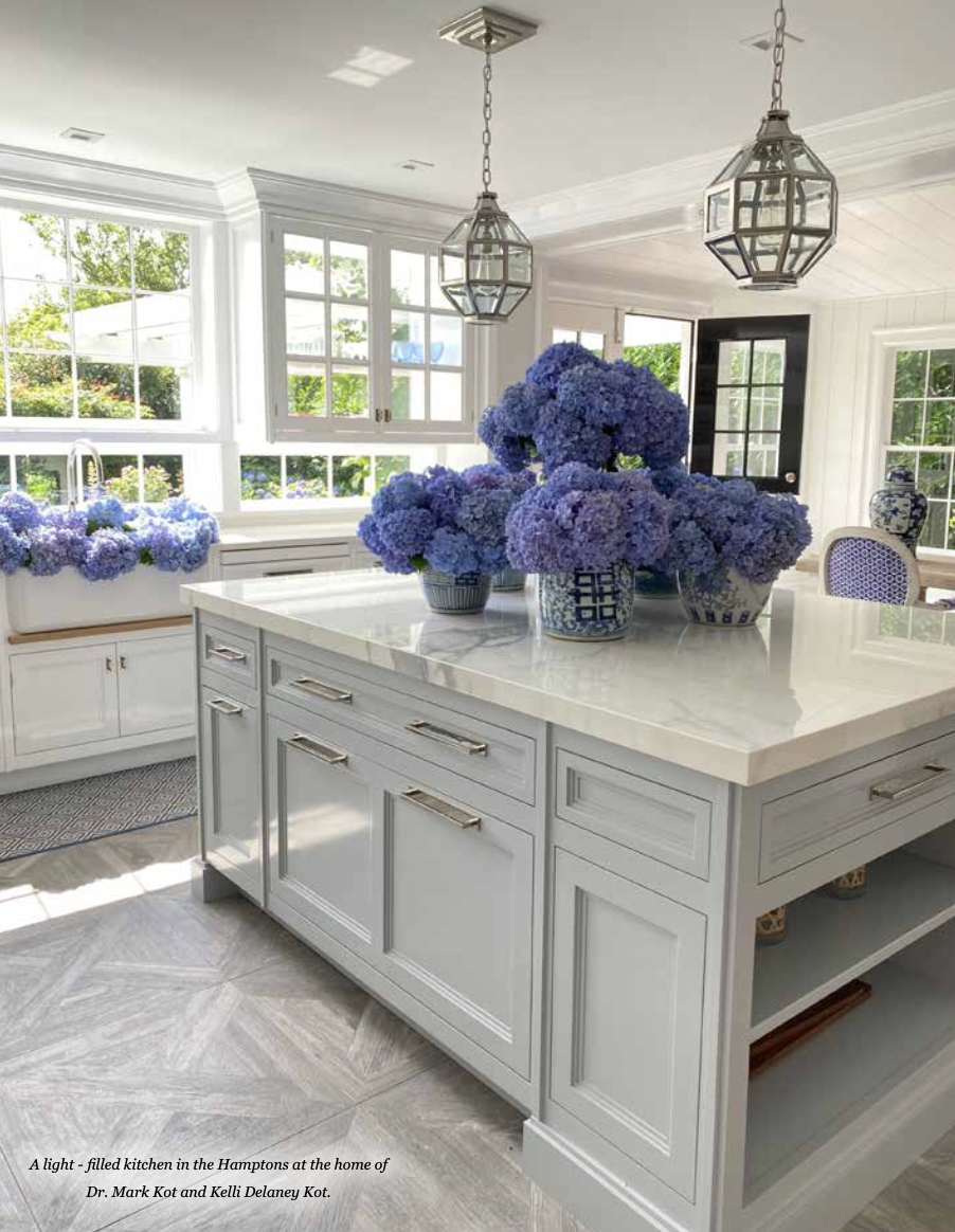 A kitchen with white cabinets and a large island with purple flowers on it.