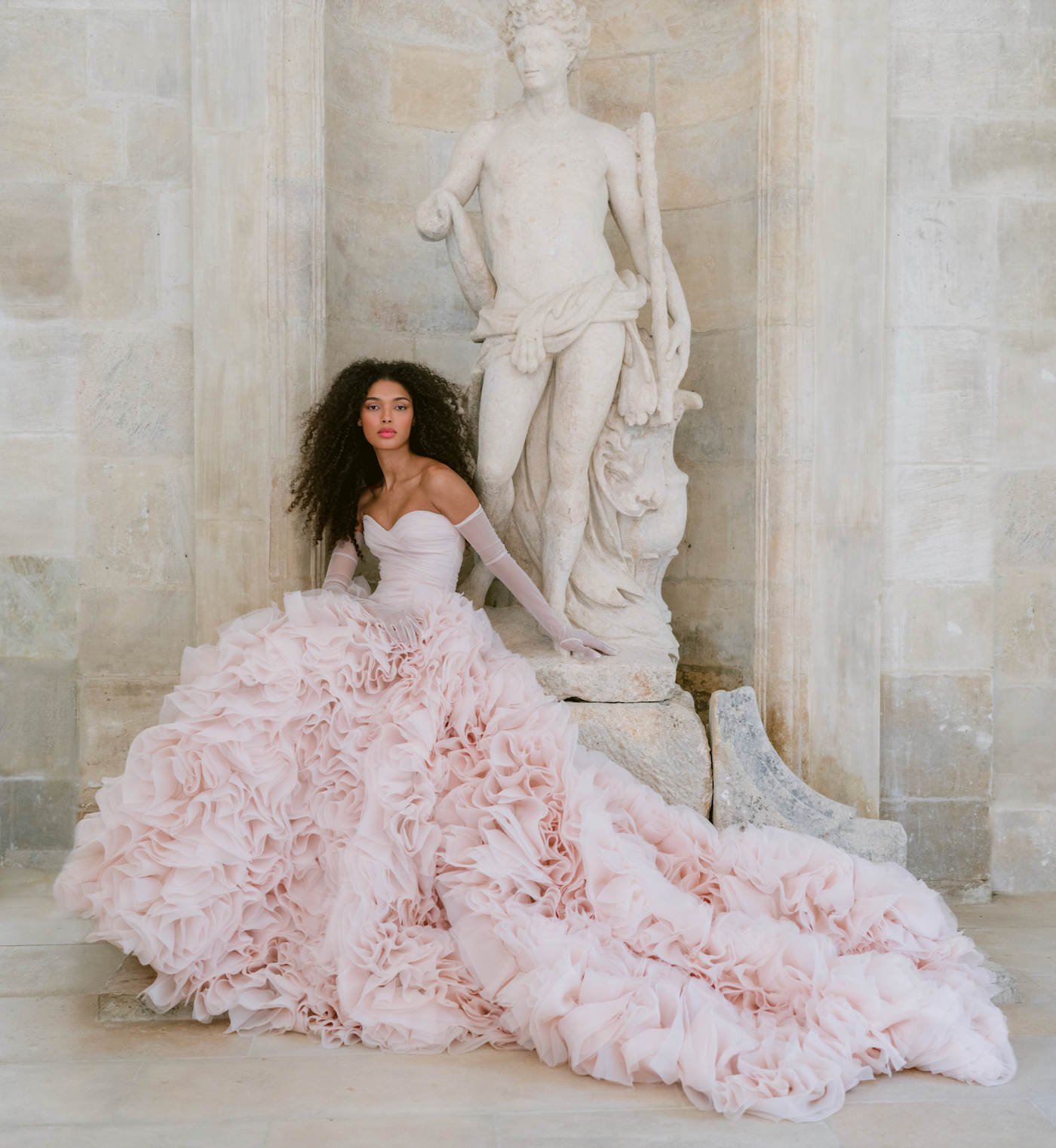 A woman in a pink dress is sitting next to a statue