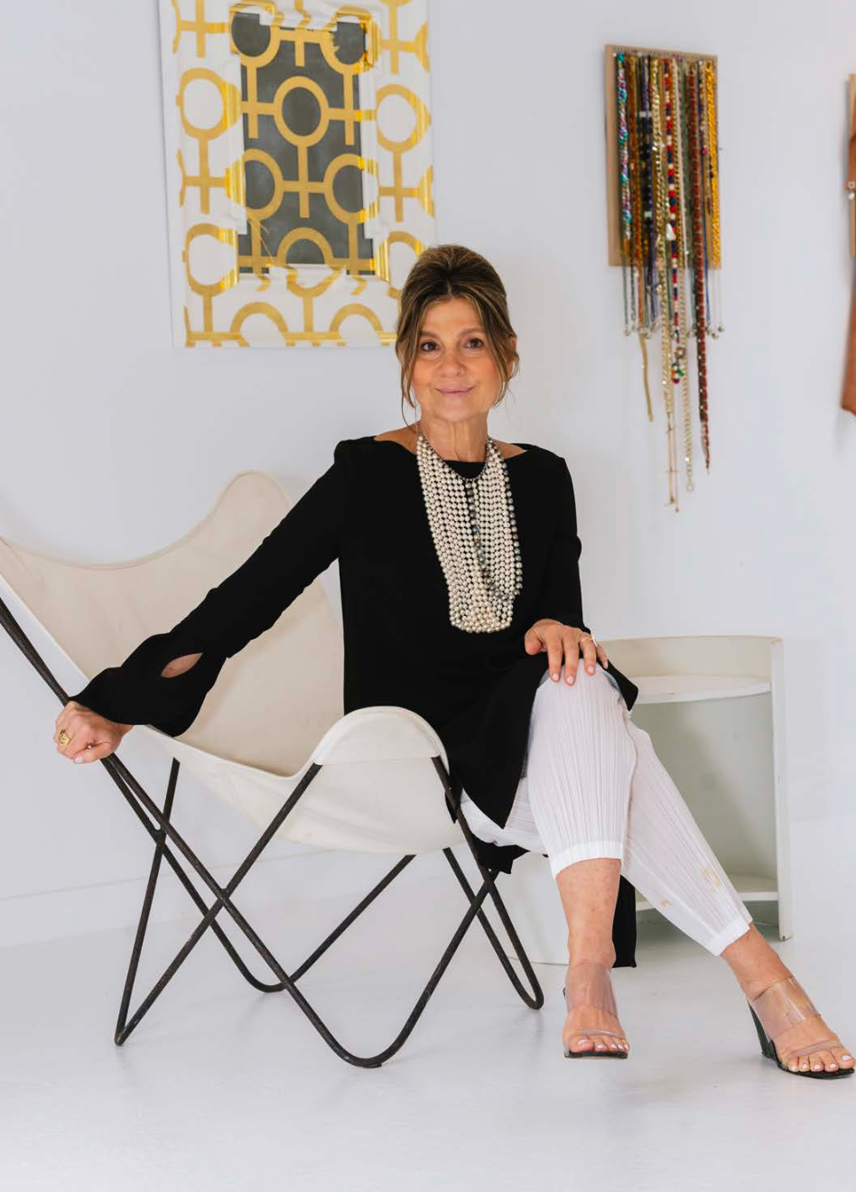 A woman in a black top and white pants is sitting in a chair