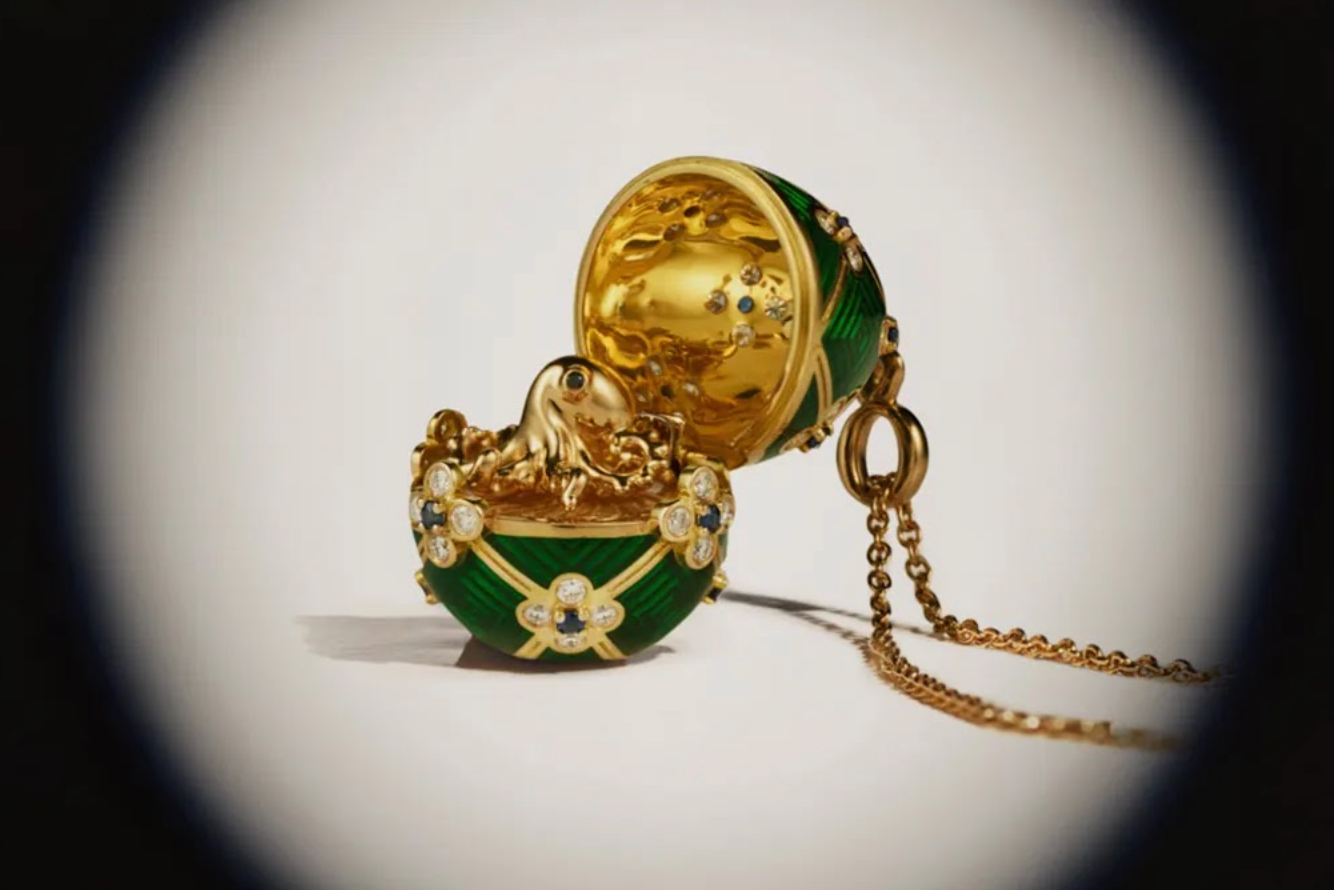 A green and gold egg shaped pendant on a chain