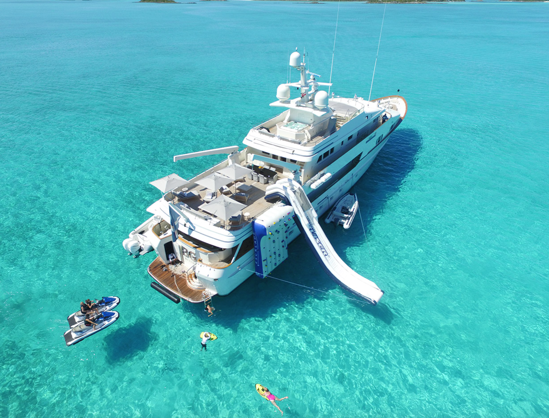 A large yacht with a water slide attached to it is in the ocean.