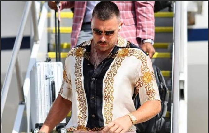 A man wearing sunglasses is walking down stairs with a suitcase.