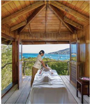 A woman is giving a man a massage in a room with a view of the ocean