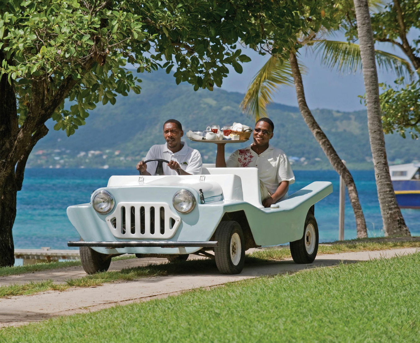 Two men are driving a small jeep with a tray on the back ..