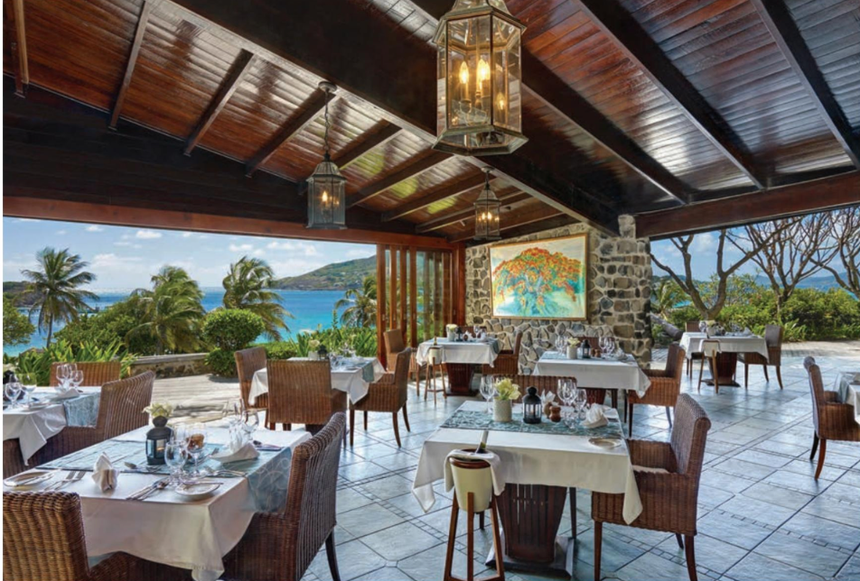 A restaurant with tables and chairs and a view of the ocean.