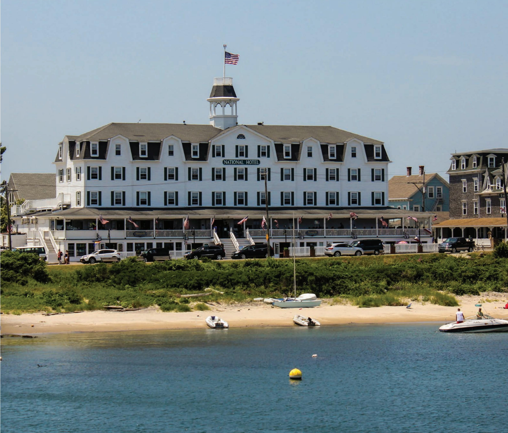 A large building with a flag on top of it sits next to a body of water