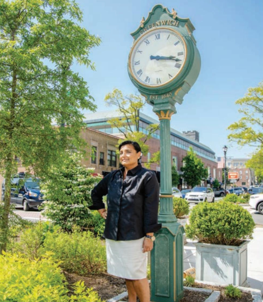 A woman is standing in front of a clock that says ' america ' on it