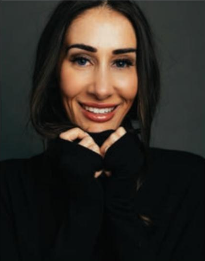 A woman wearing a black turtleneck is smiling and covering her face with her hands