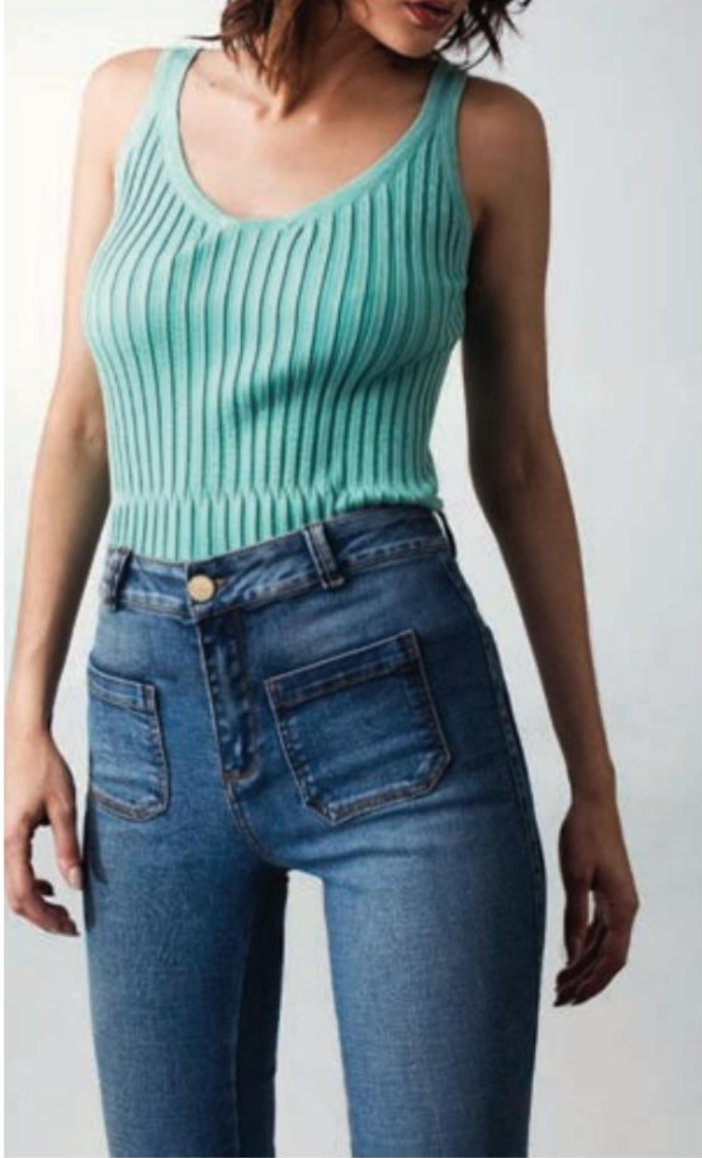A woman is wearing a green tank top and blue jeans.