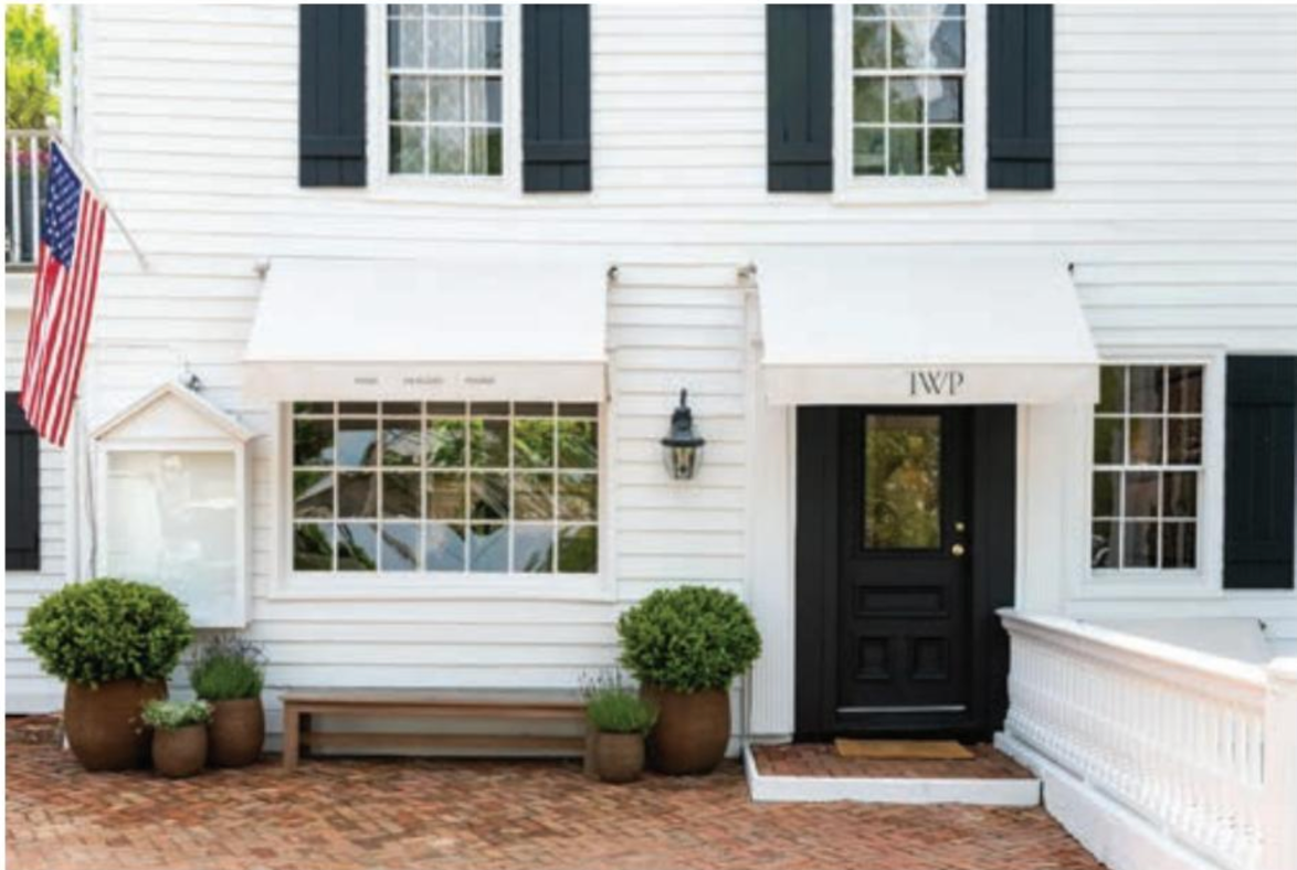 A white house with black shutters and a black door