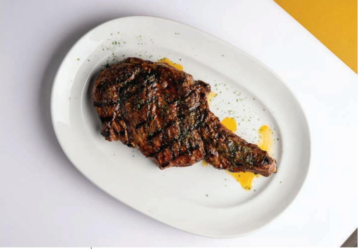 A white plate with a steak on it on a table