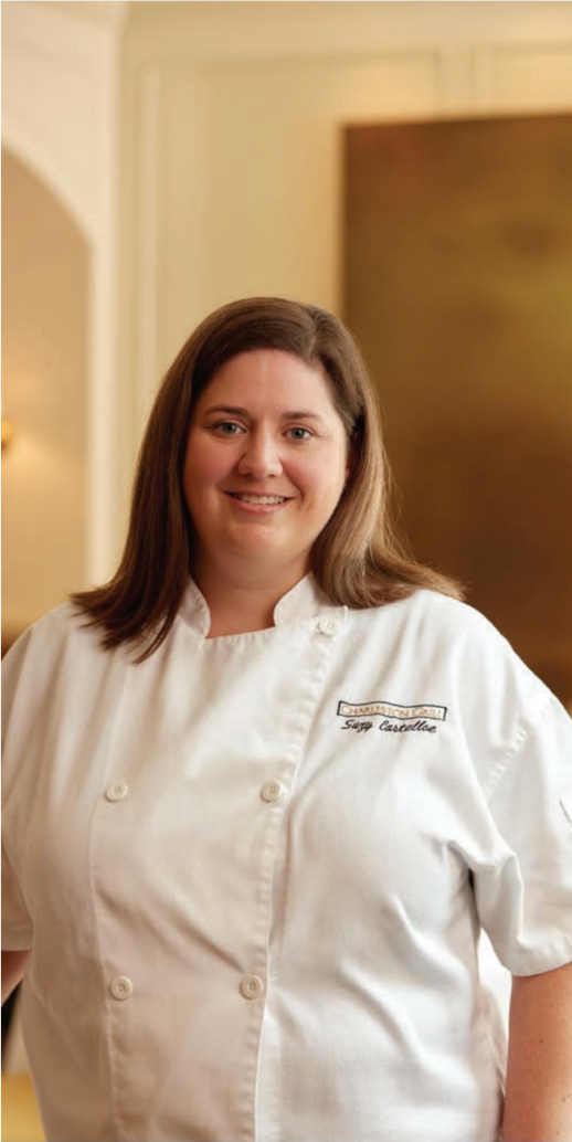 A woman in a white chef 's coat is smiling for the camera.