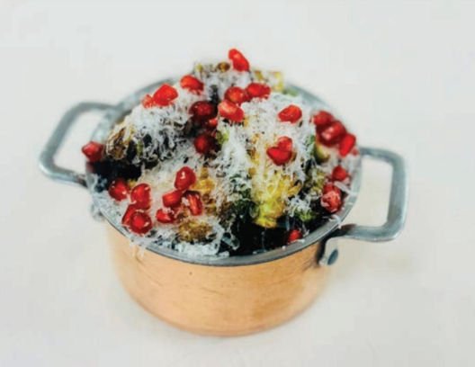 A copper pot filled with rice and pomegranate seeds.