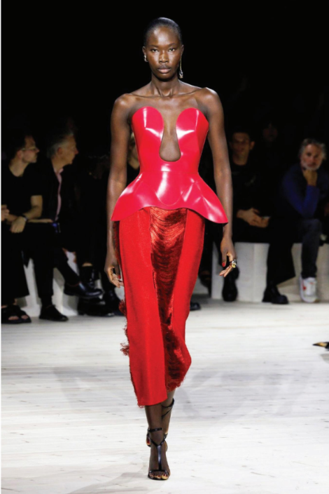 A model walks down the runway wearing a red dress