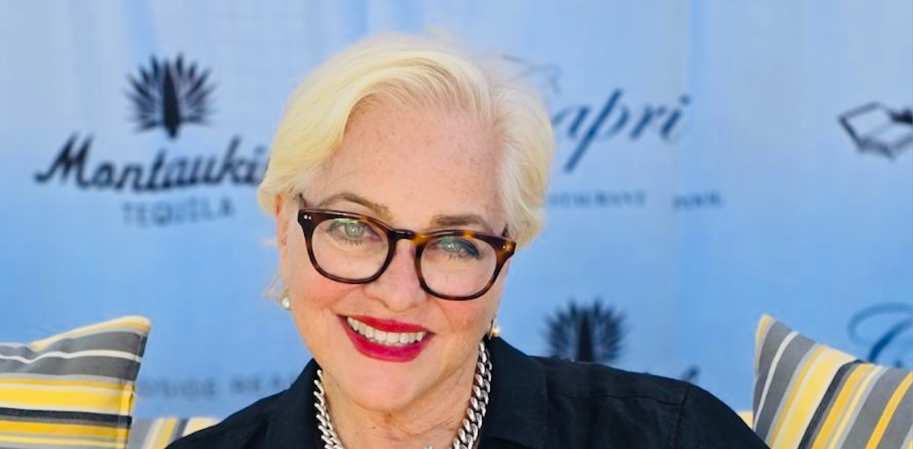 A woman wearing glasses and a black shirt is smiling for the camera.