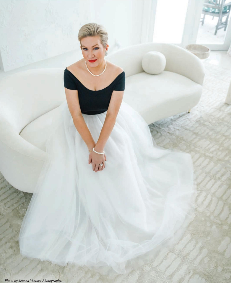 A woman in a black top and white skirt is sitting on a white couch