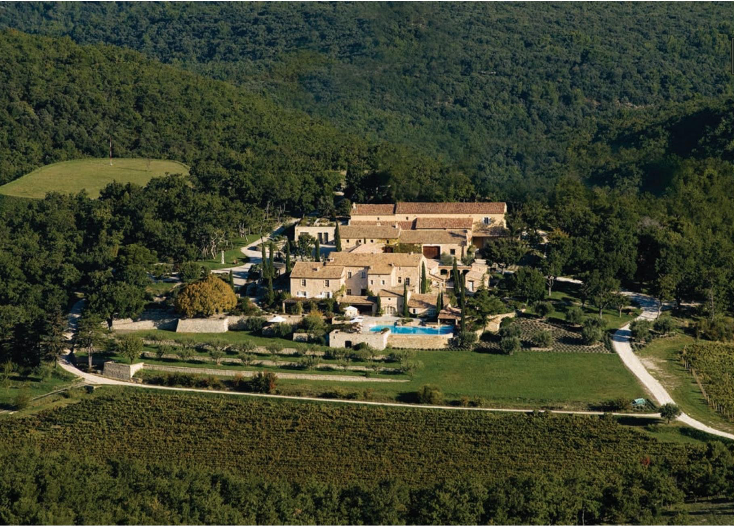 An aerial view of a large house in the middle of a forest