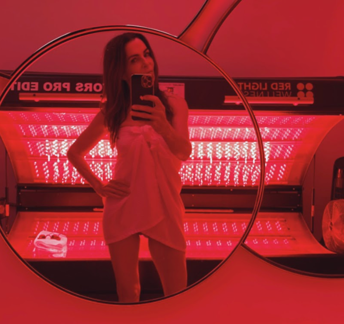 A woman taking a picture of herself in a mirror with a red background