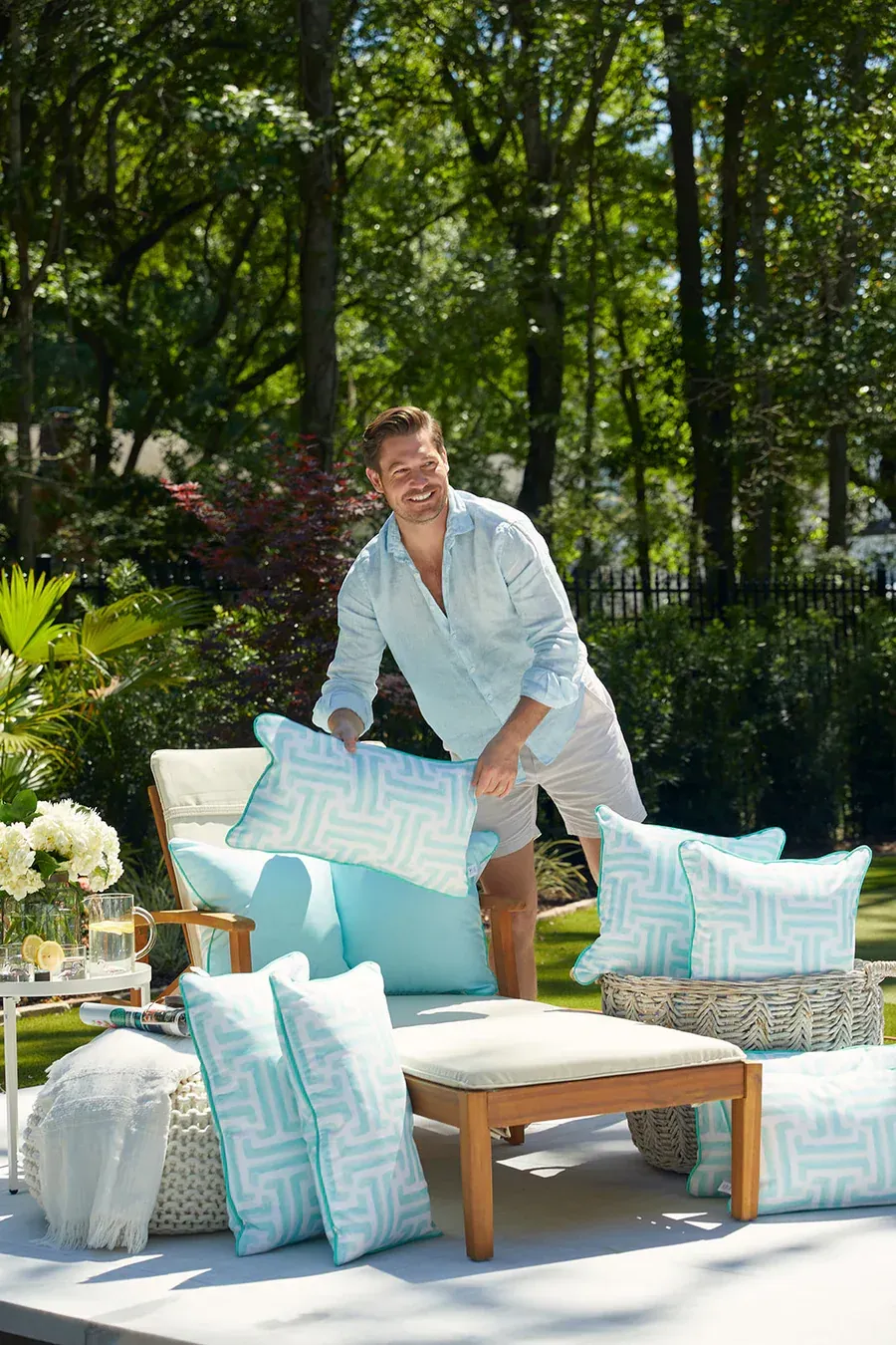 A man is standing next to a couch with pillows on it.