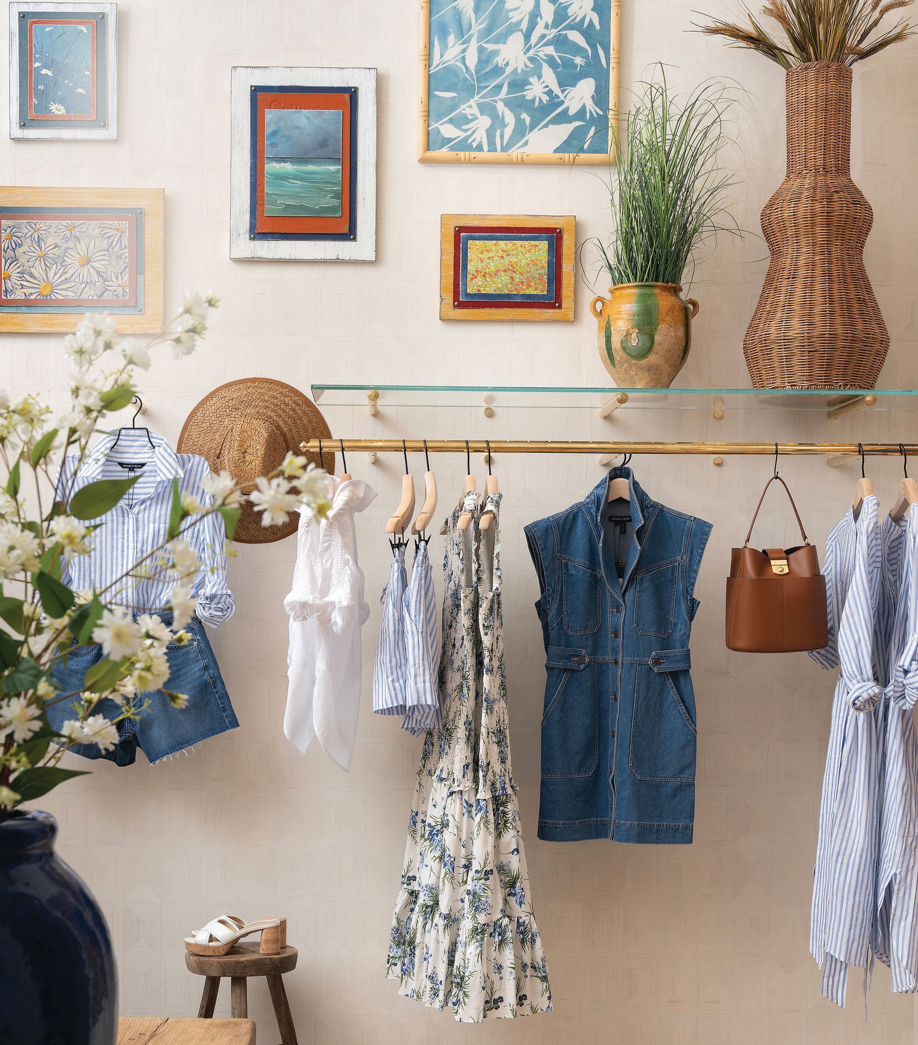 A room with clothes hanging on a rack and a vase of flowers