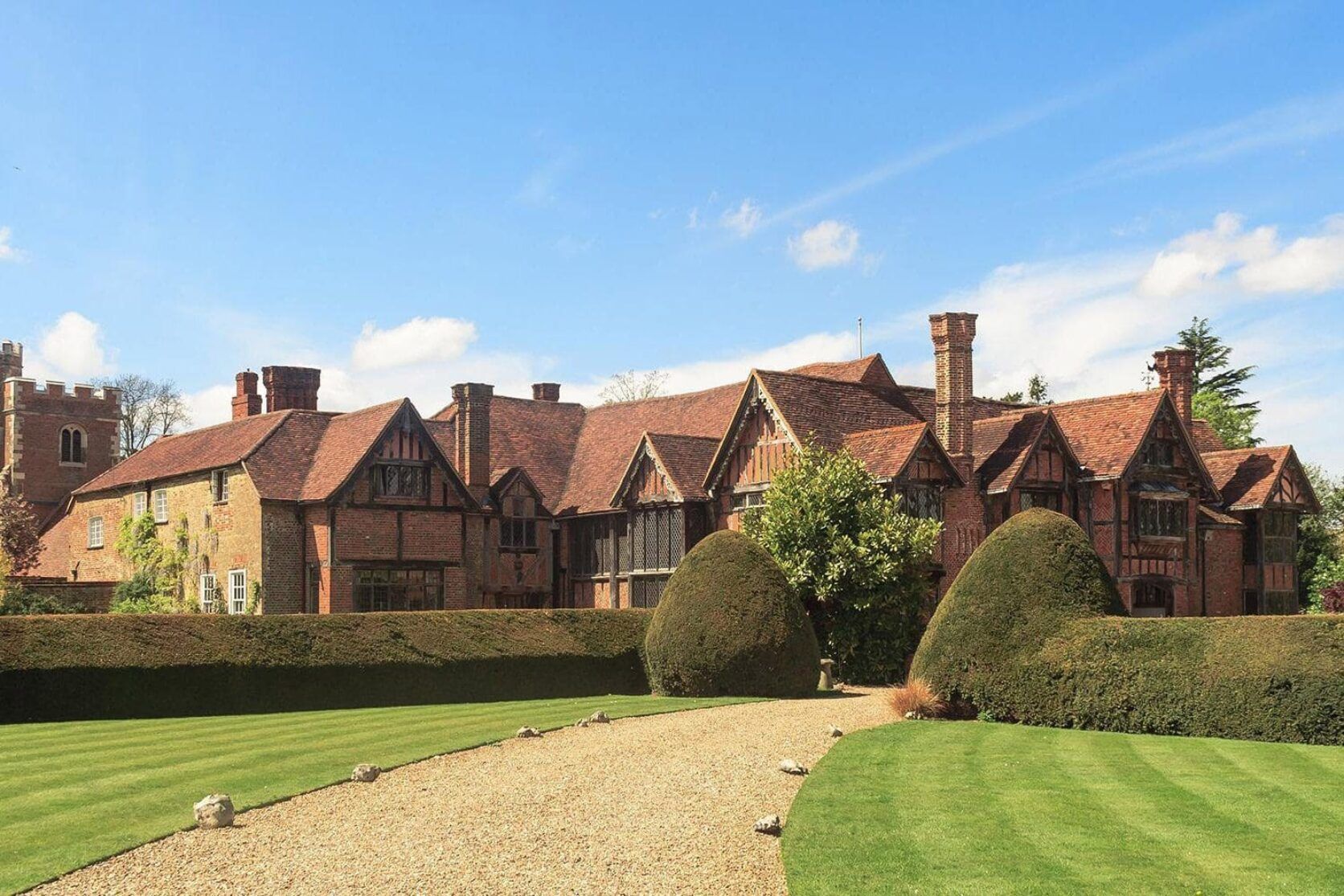 A large brick house with a gravel driveway leading to it.