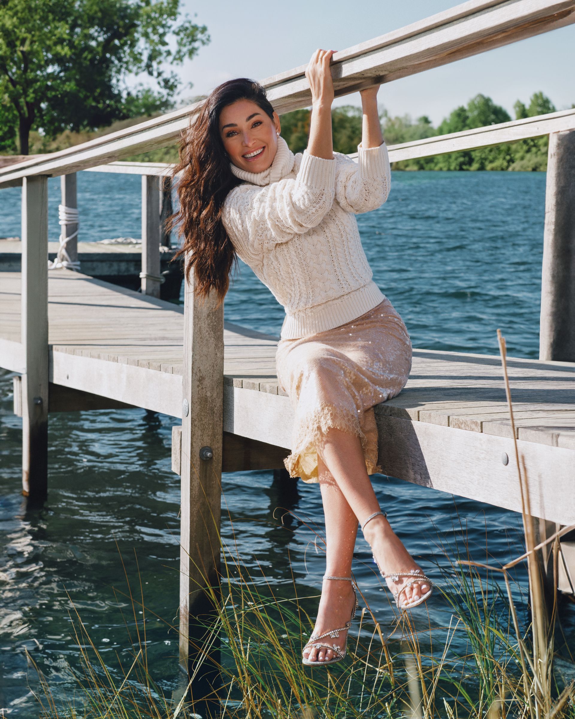 A woman is sitting on a dock overlooking a body of water.