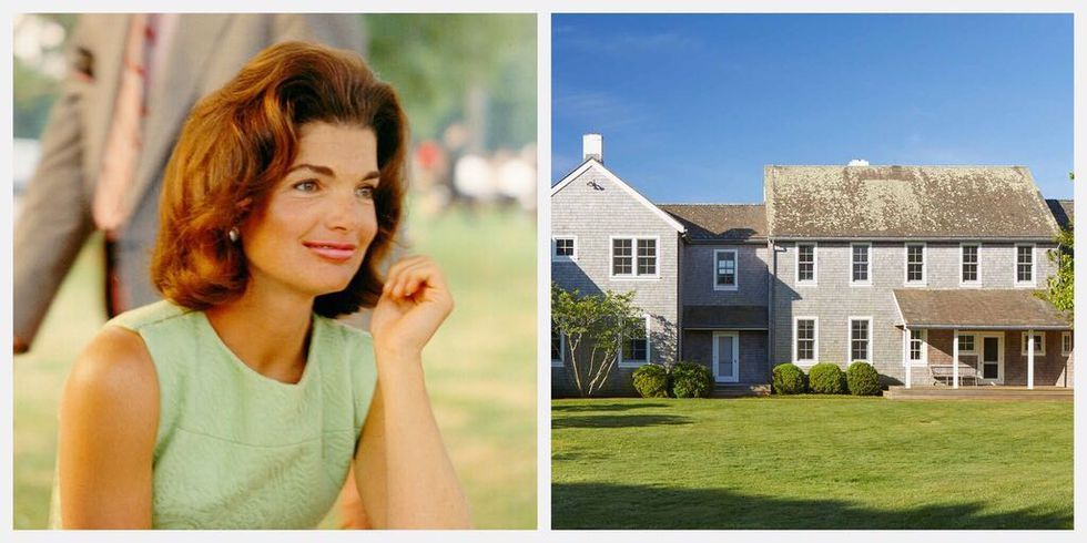 A woman is sitting in a field next to a house