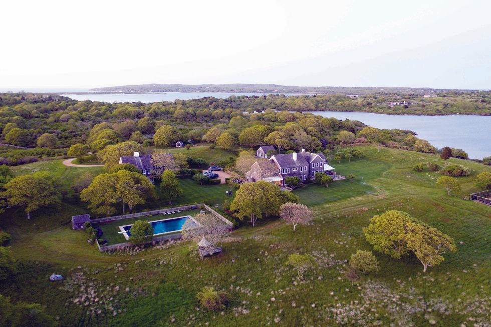 An aerial view of a large house surrounded by trees and a body of water.