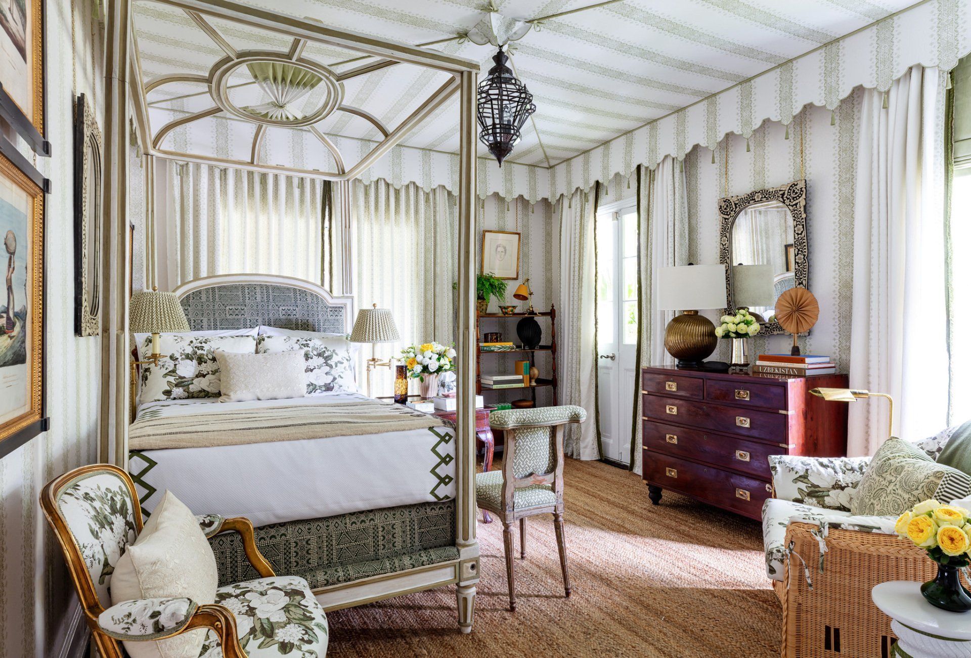 A bedroom with a canopy bed , chairs , dresser and mirror.