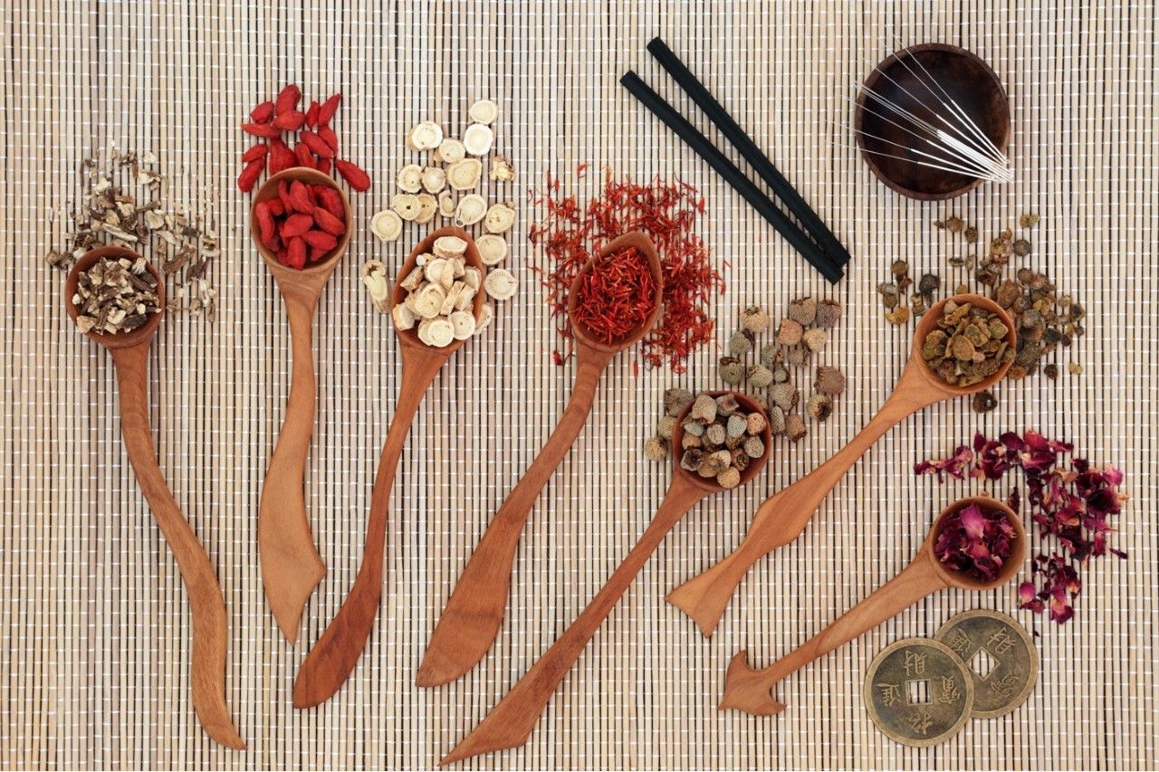 A table topped with wooden spoons filled with different types of herbs and spices.