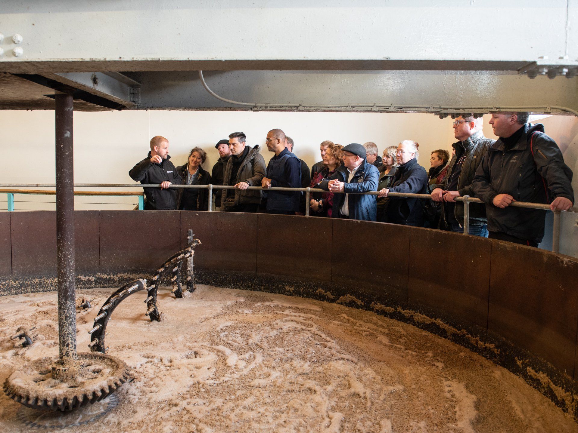 Photo of group of people on a tour looking at fermenting alcohal