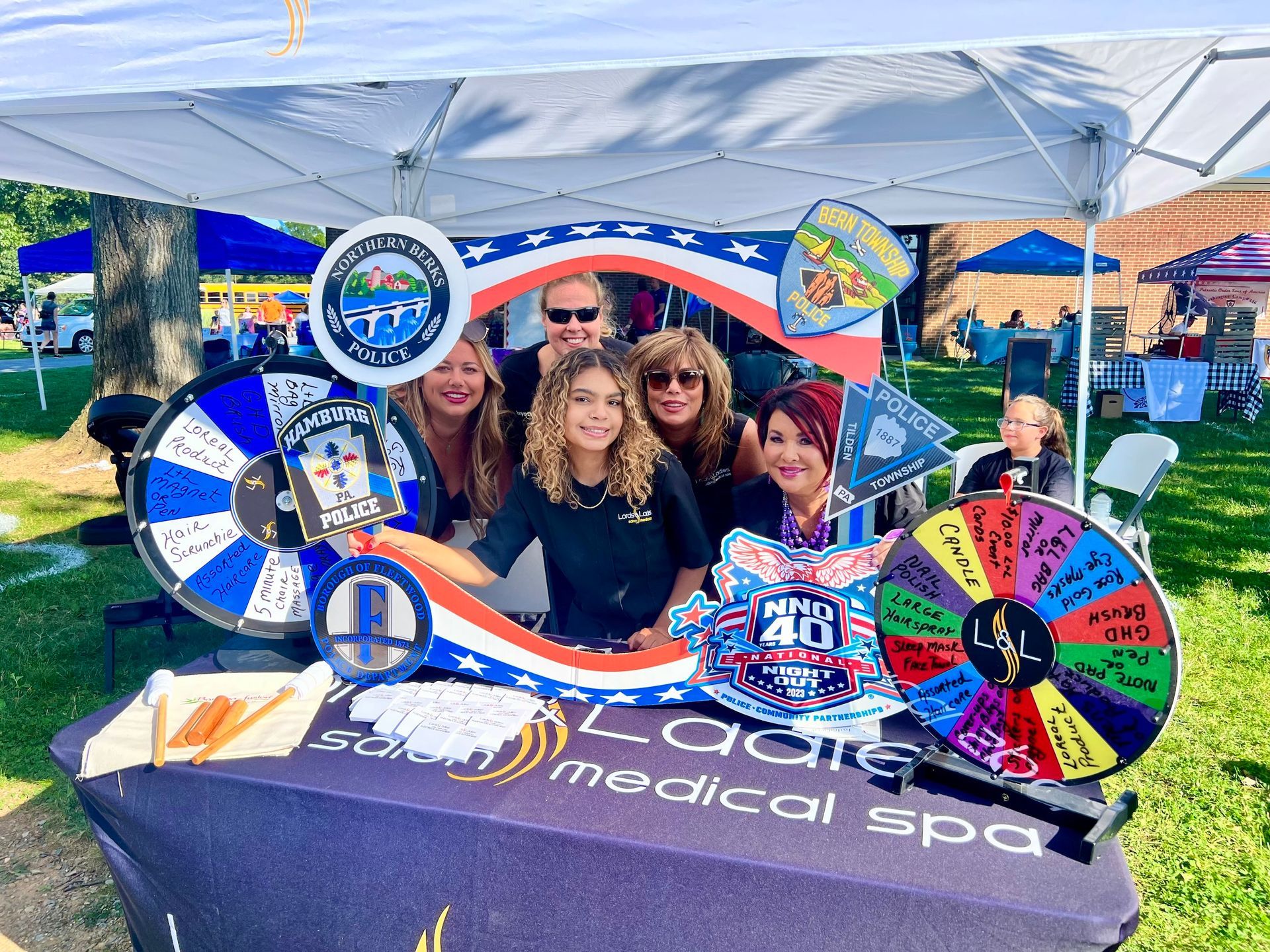 A group of people are standing around a table with a wheel of fortune on it.