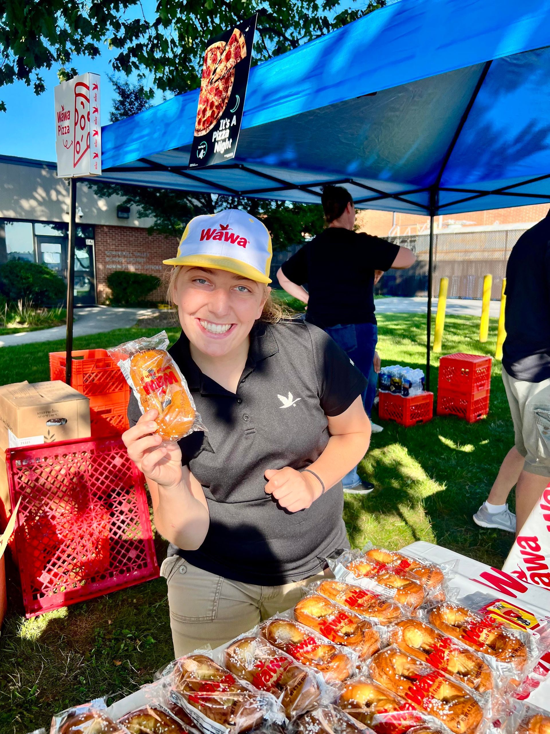 A woman is standing in front of a table holding a bag of food.