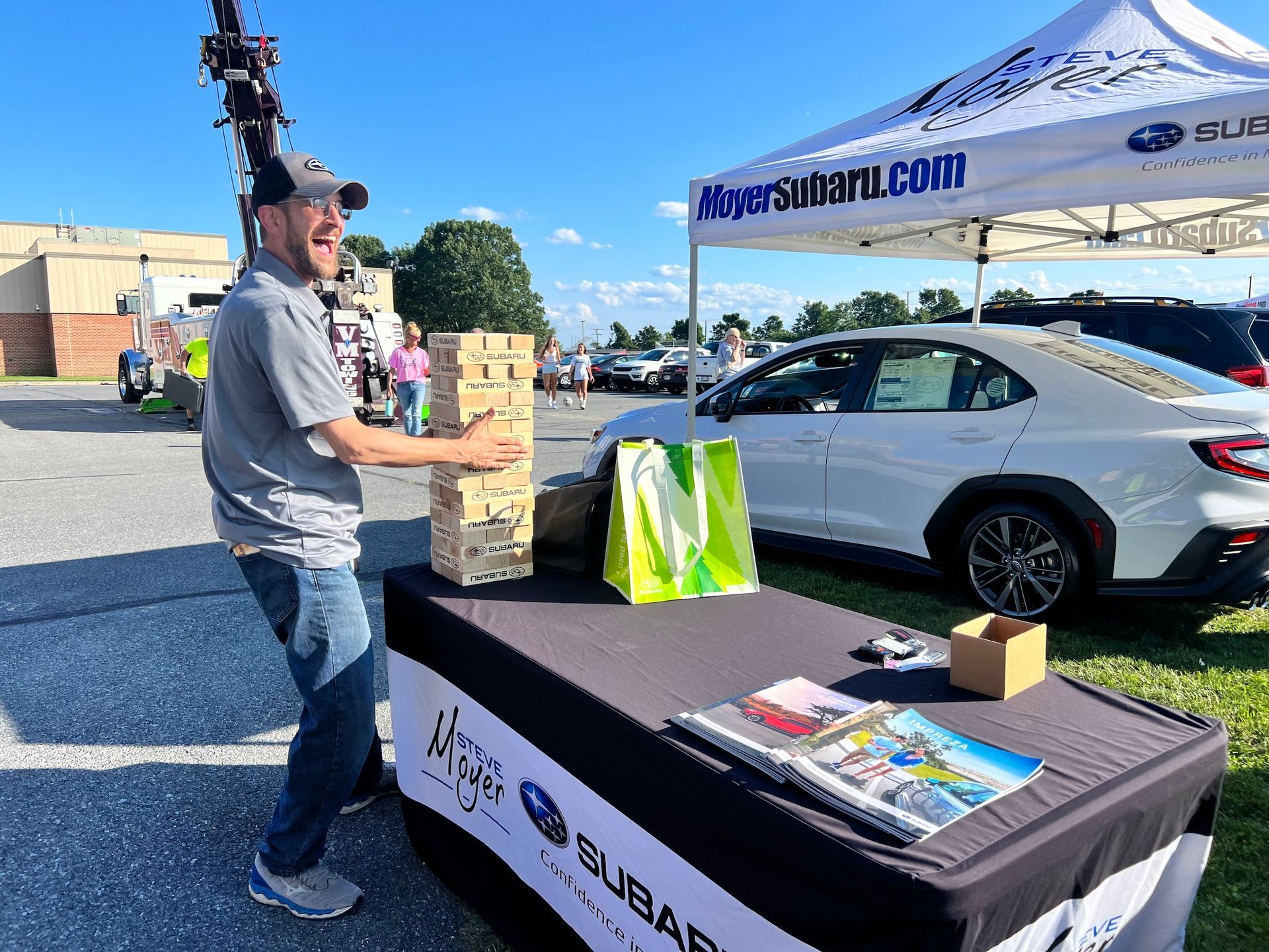 A man is standing next to a table with a car in the background.
