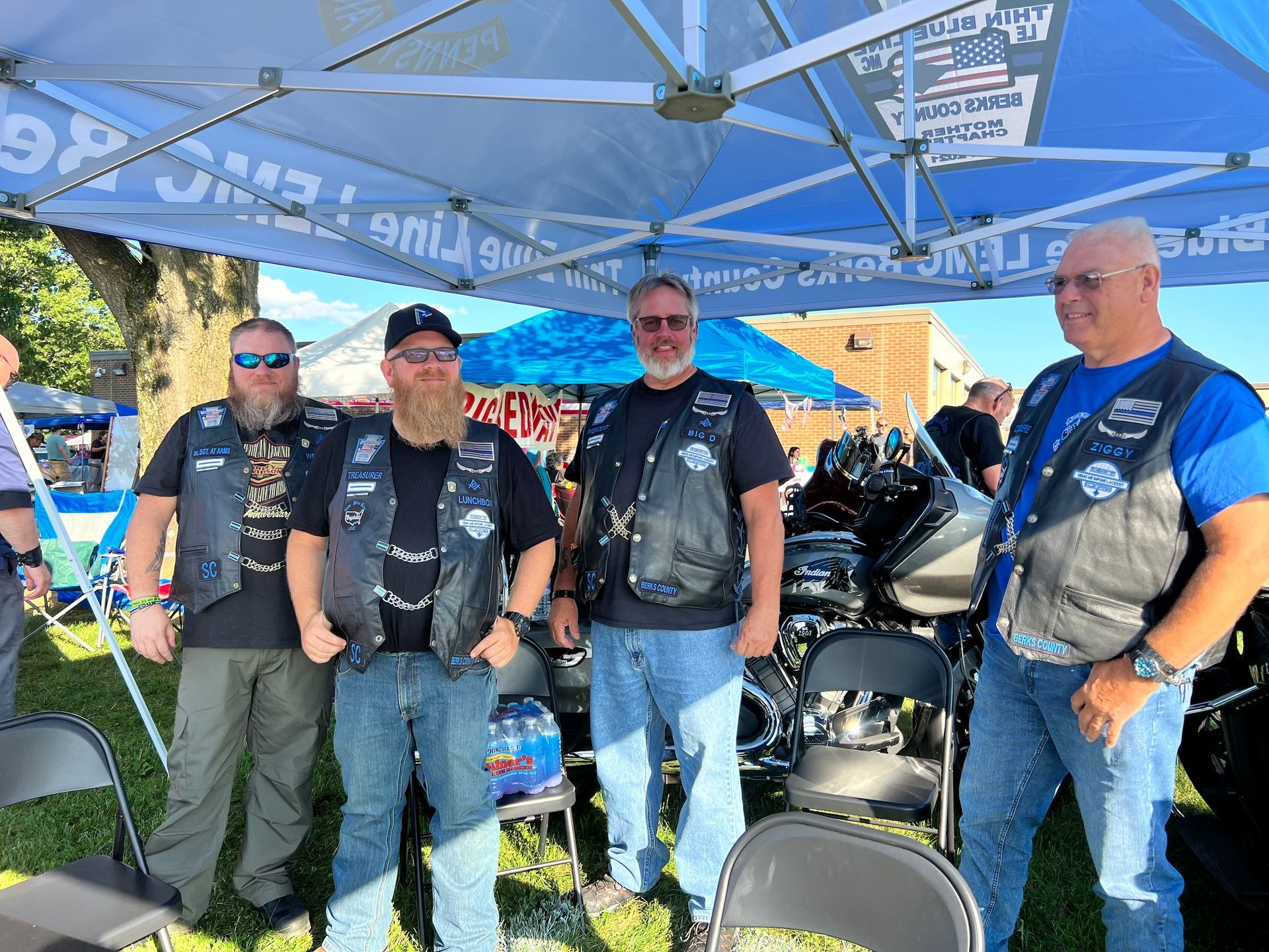 A group of men are standing under a blue tent.