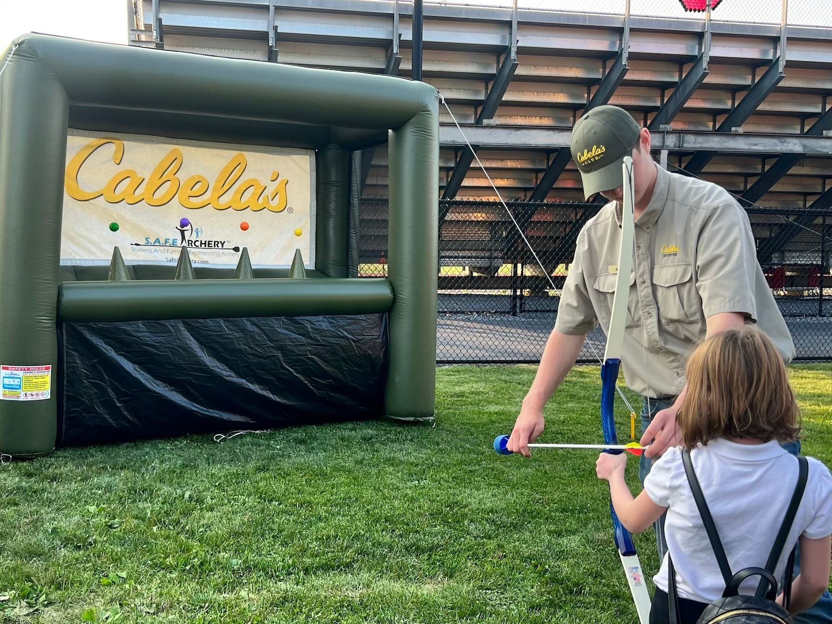 A man and a little girl are playing a game of archery.