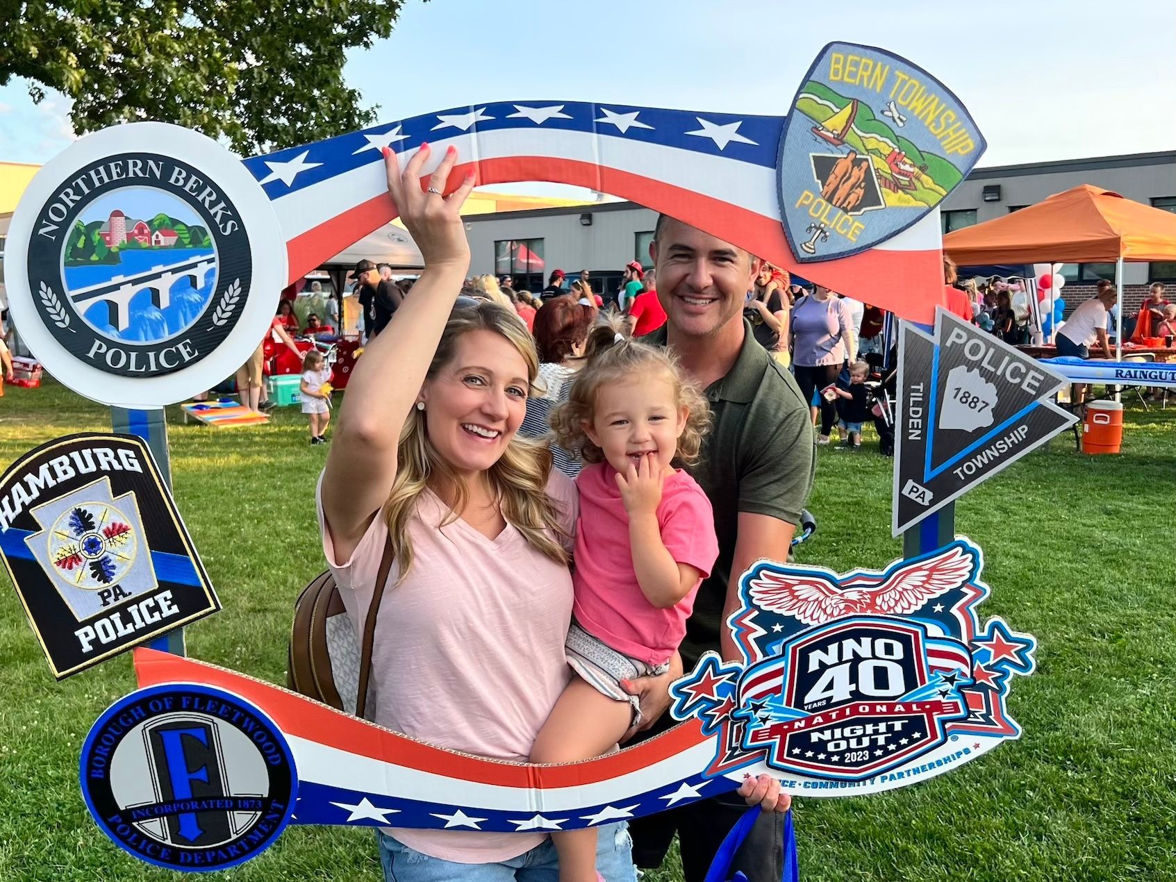 A man and woman are holding a little girl in front of a picture frame.