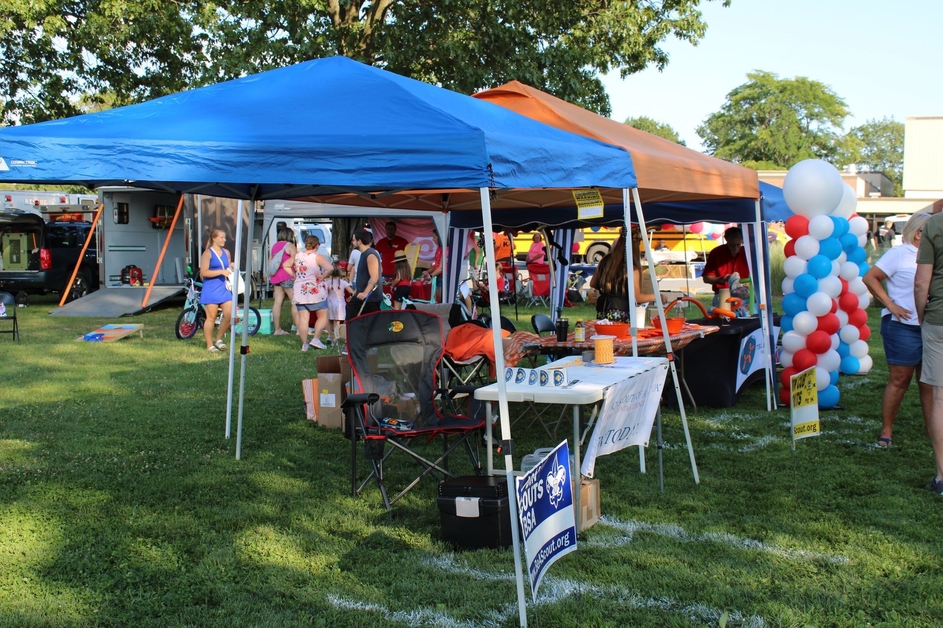 A group of people are standing under tents in a field.