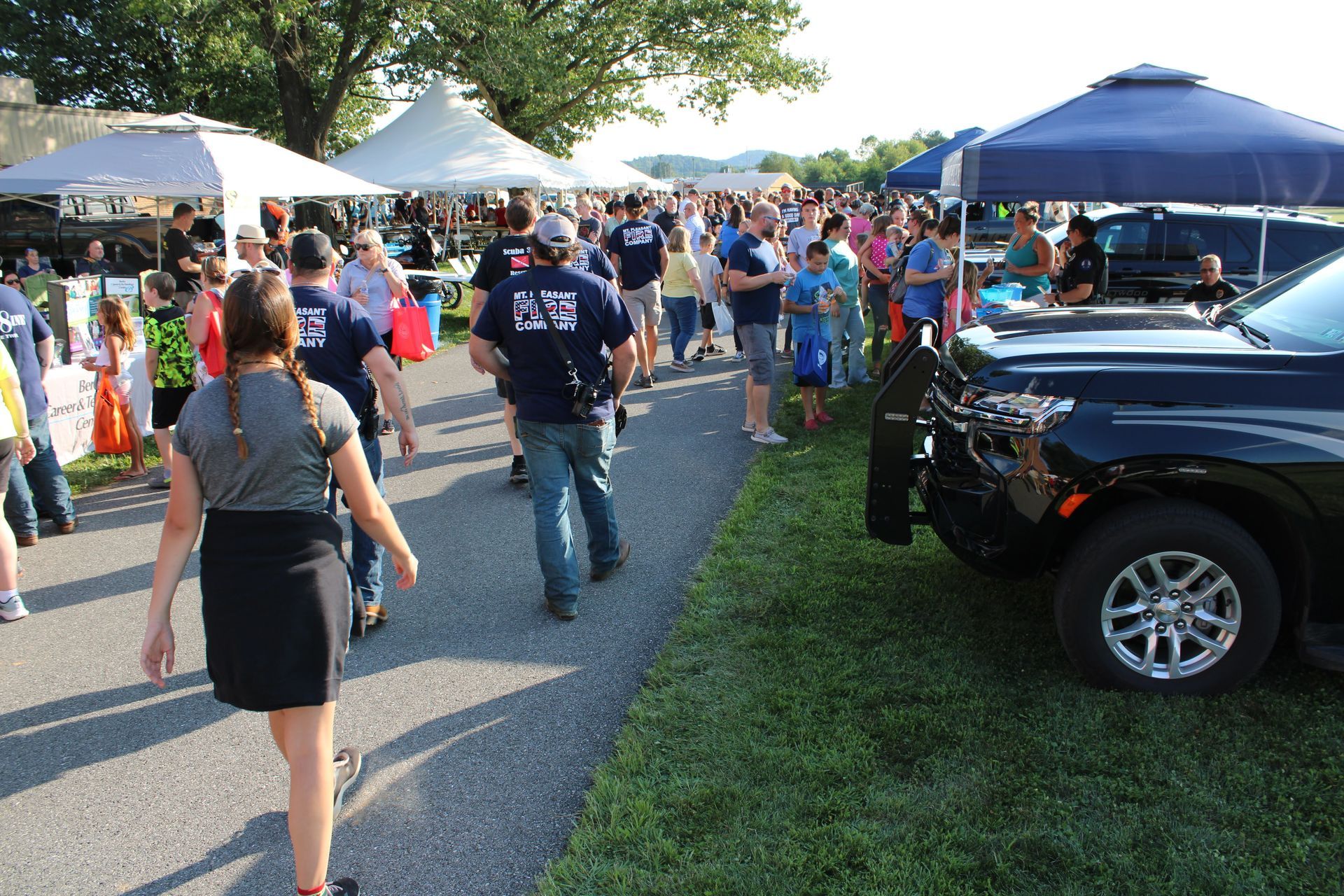 A crowd of people are gathered around a black truck
