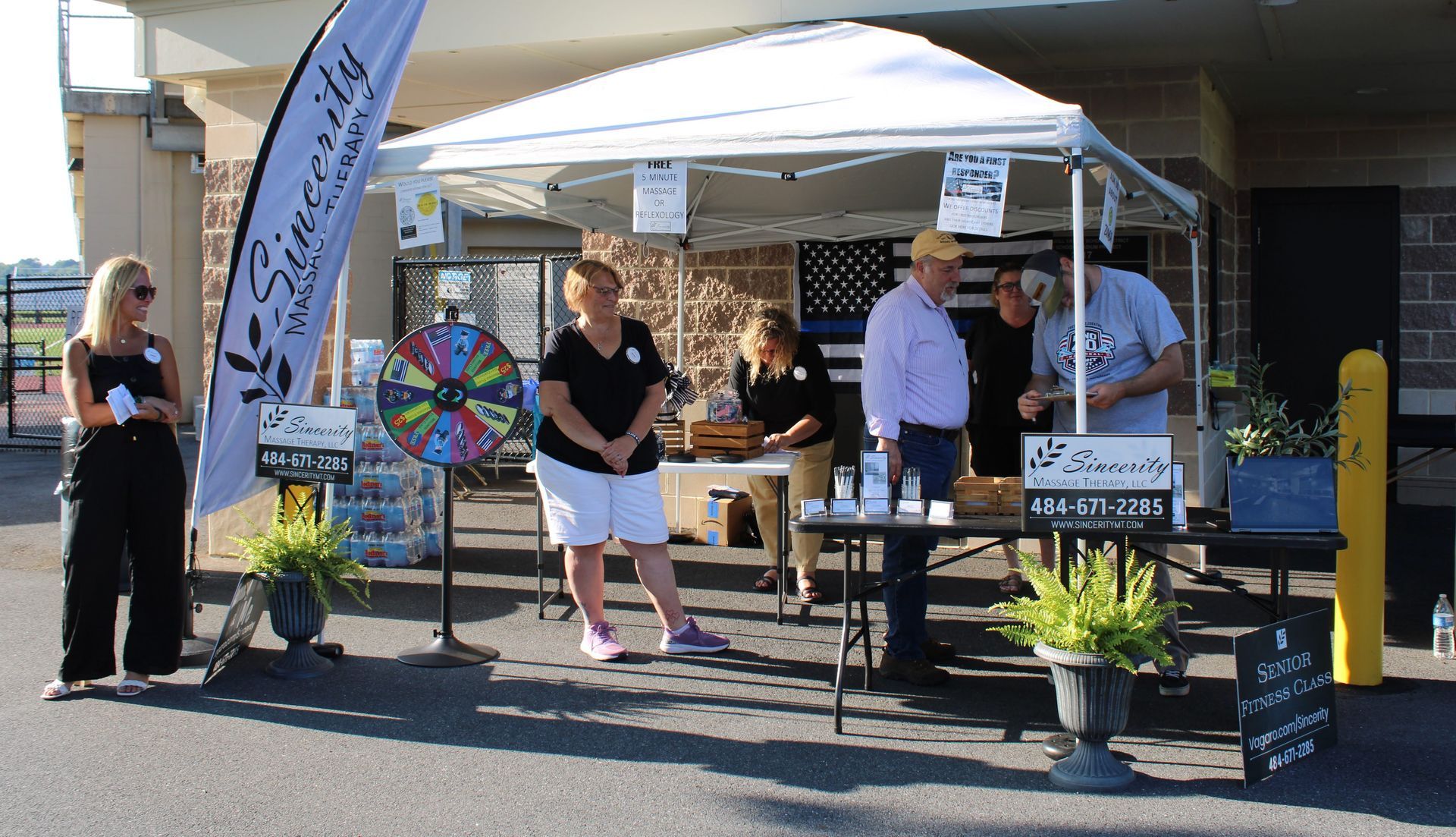 A group of people standing around a table under a tent.