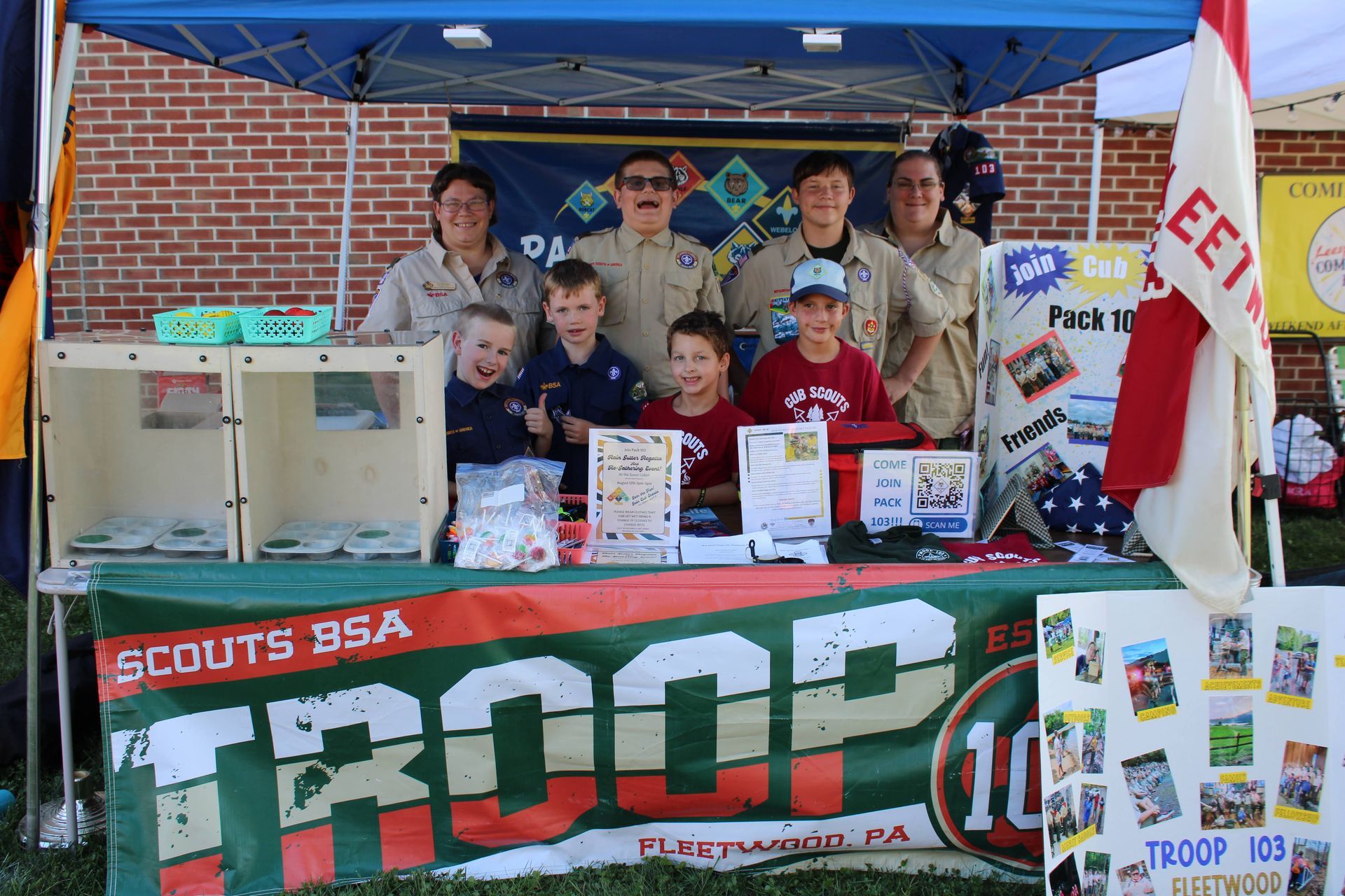 A group of scouts are posing for a picture in front of a troop table
