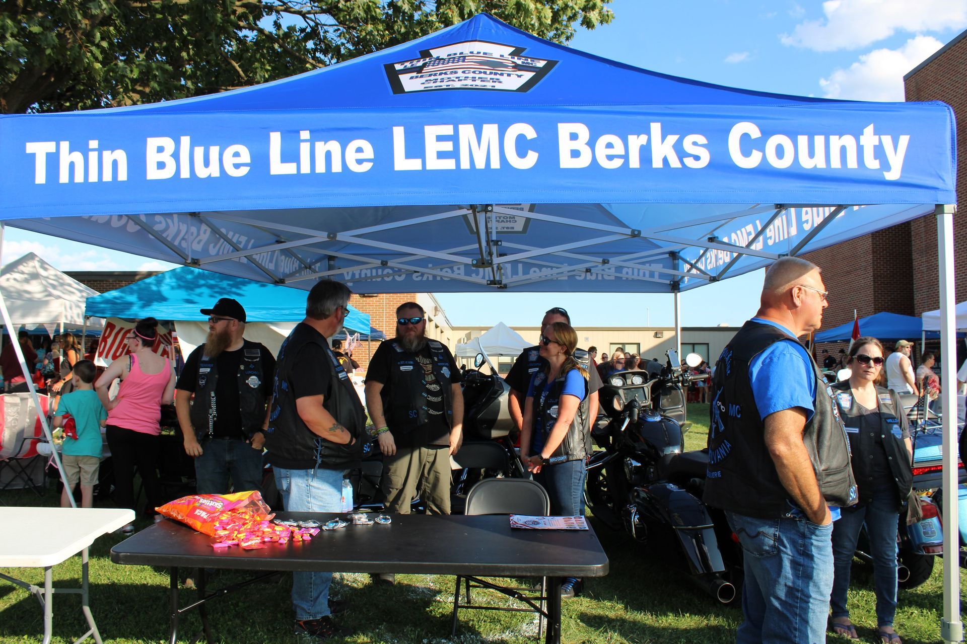 A group of people standing under a blue tent that says thin blue line lemc berks county