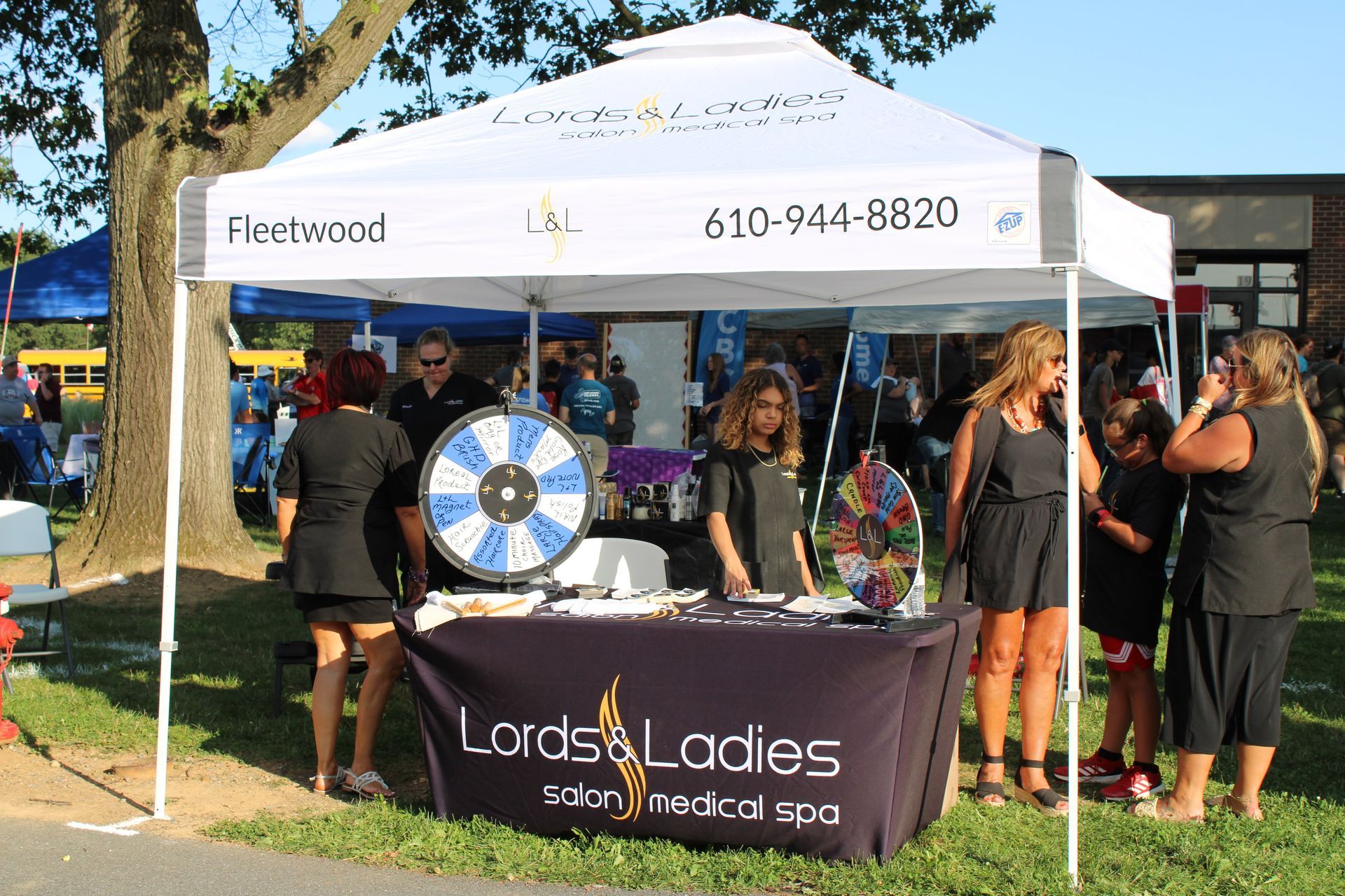 A group of people standing around a table under a tent that says lords & ladies