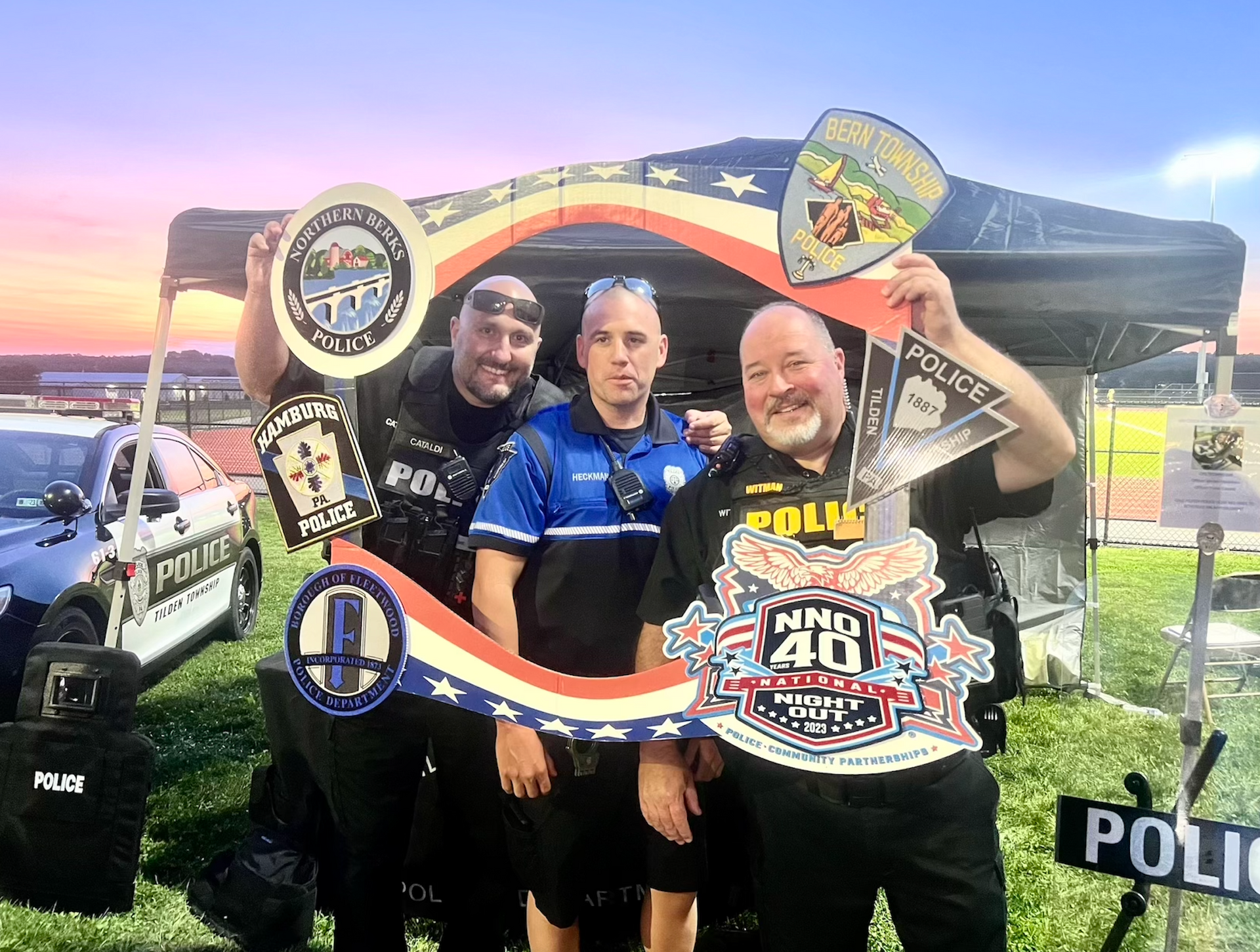 A group of police officers are posing for a picture in front of a tent.