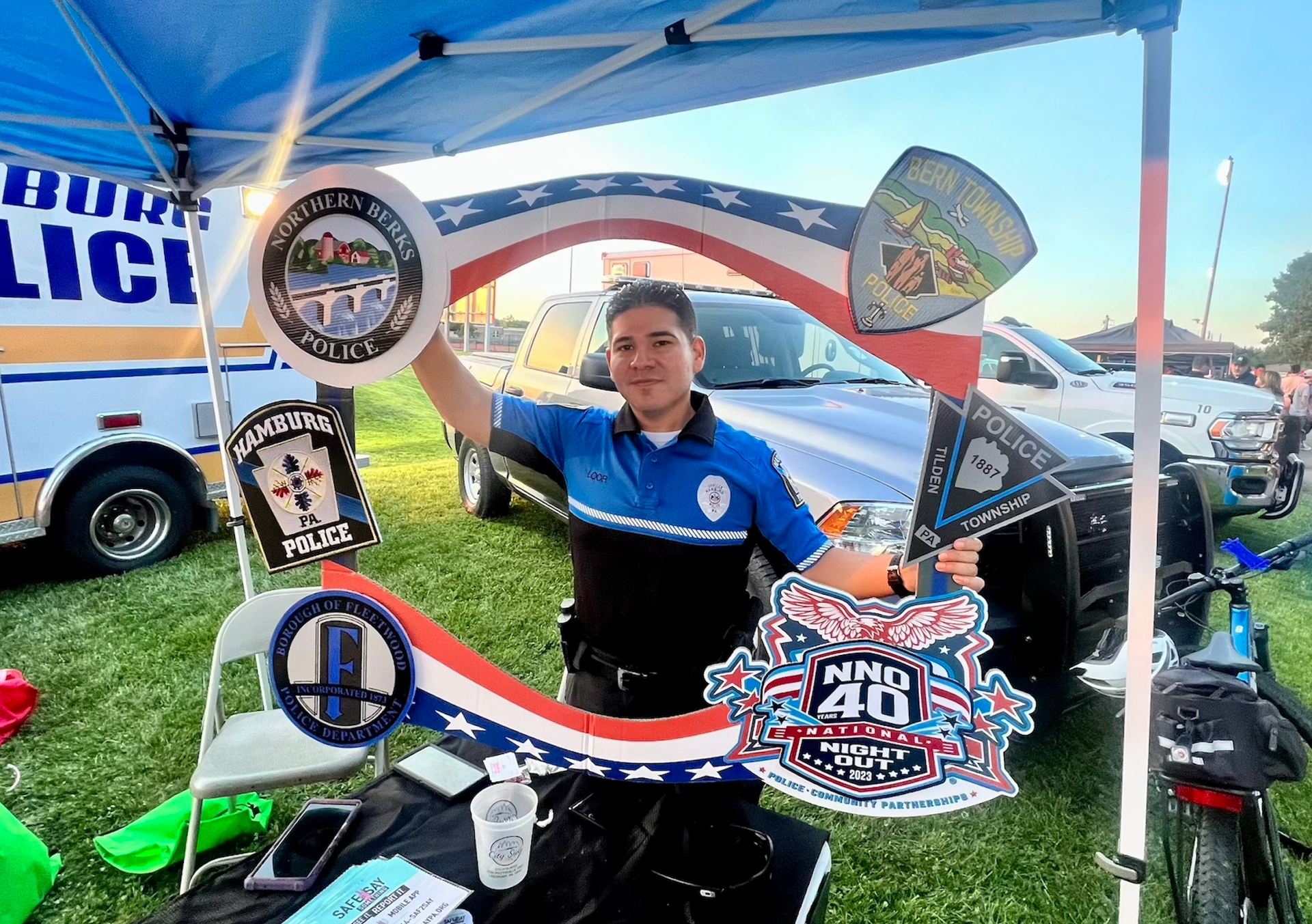 A woman in a police uniform is standing in front of a tent holding a picture frame.