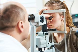 Optometrist examines a woman's eye with a slit lamp in a clinic.